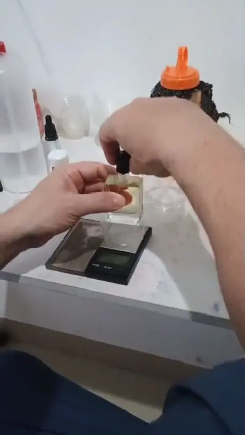 Hands preparing a perfume bottle at the workbench